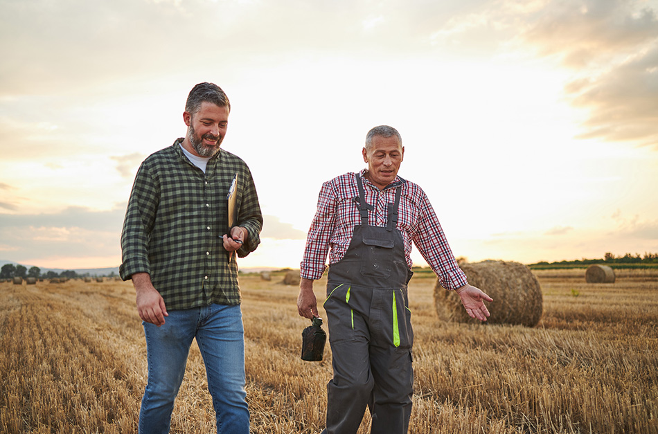 Mid adult man walking alongside a senior landowner and having a discussion.