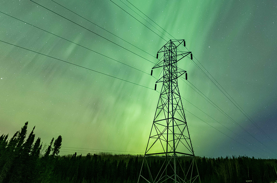 Power lines with the northern lights in the sky above.